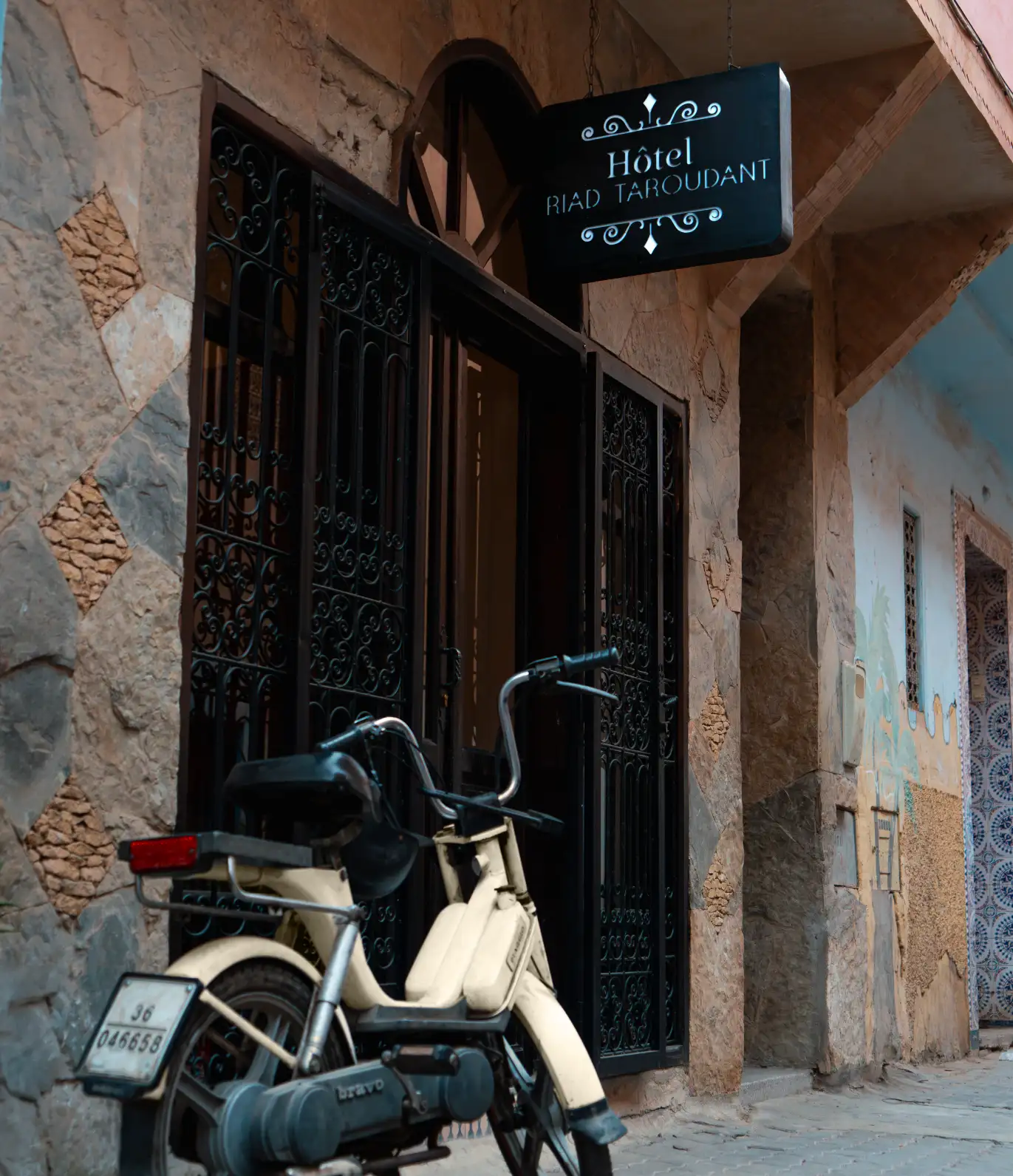 Entrée de l’Hôtel Riad Taroudant, avec une porte en bois sculptée.